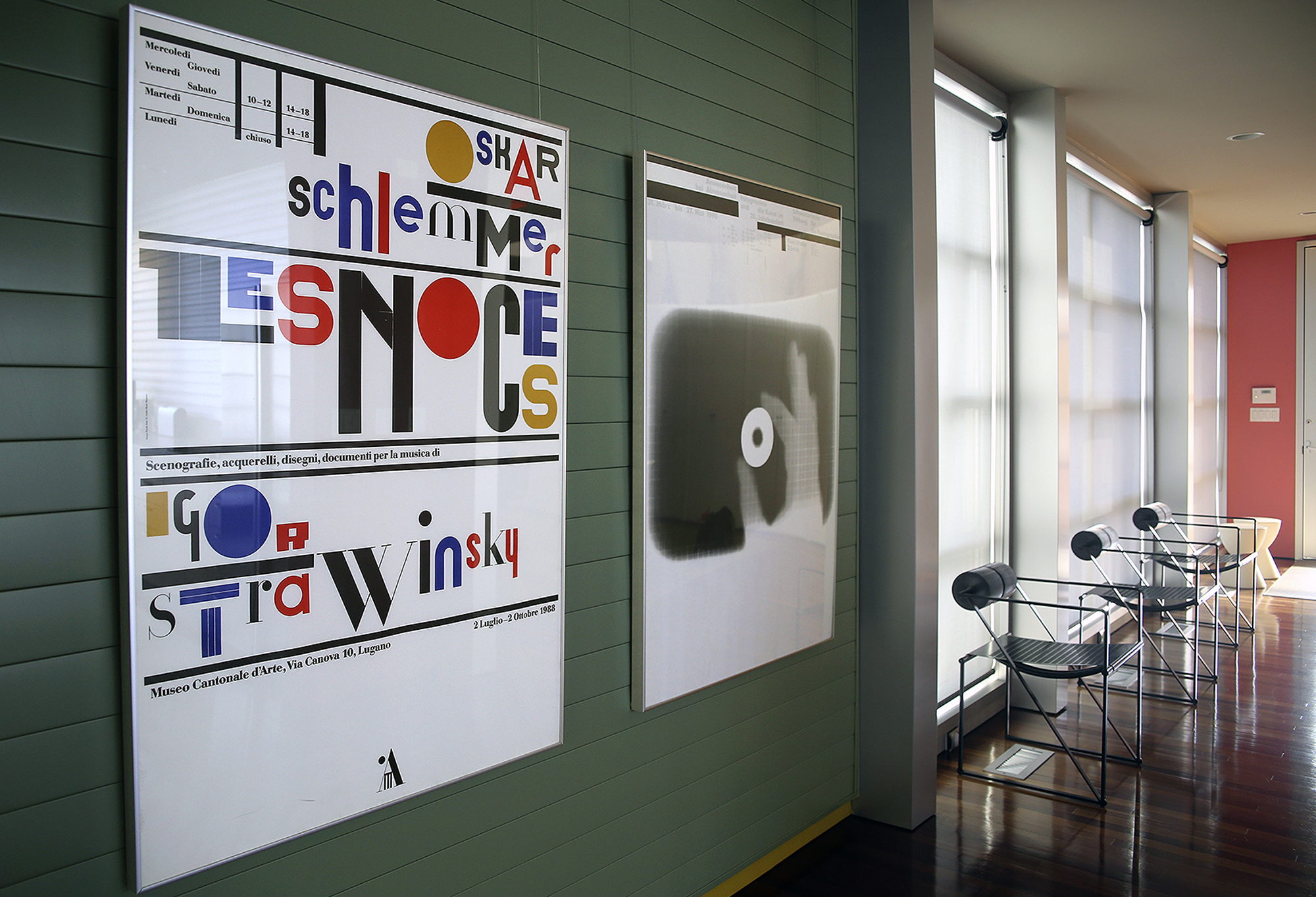 Typographic posters and modern chairs against window wall; green, red, blue, black