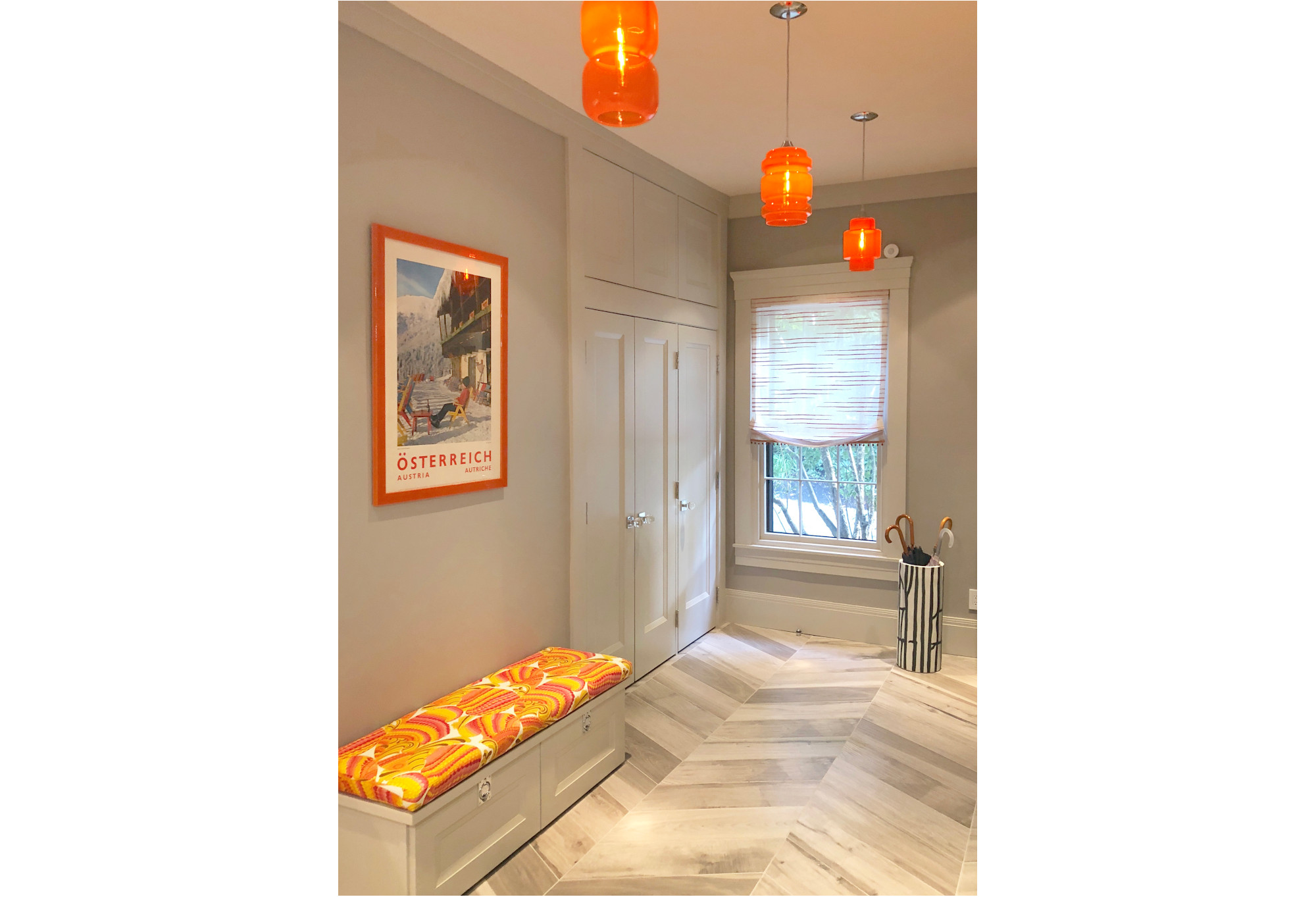 bright hallway with orange lights, bench, and framed ski poster on wall; orange, white, black